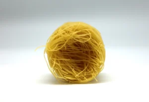 A single nest of dry Capellini pasta, also known as angel hair, showcasing its ultra-fine strands before cooking.