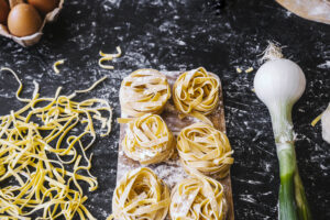 Onion lying near uncooked pasta