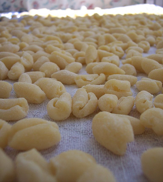 A close-up view of fresh handmade cavatelli pasta arranged in rows on a wooden board.