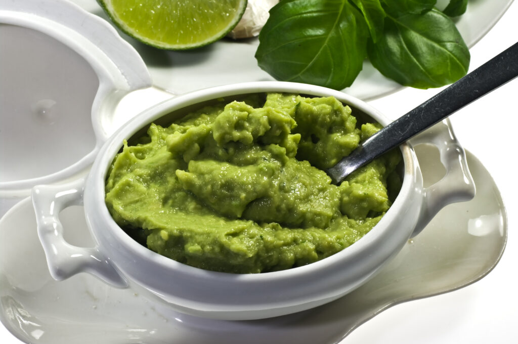 A bowl of fresh creamy avocado pasta sauce garnished with basil