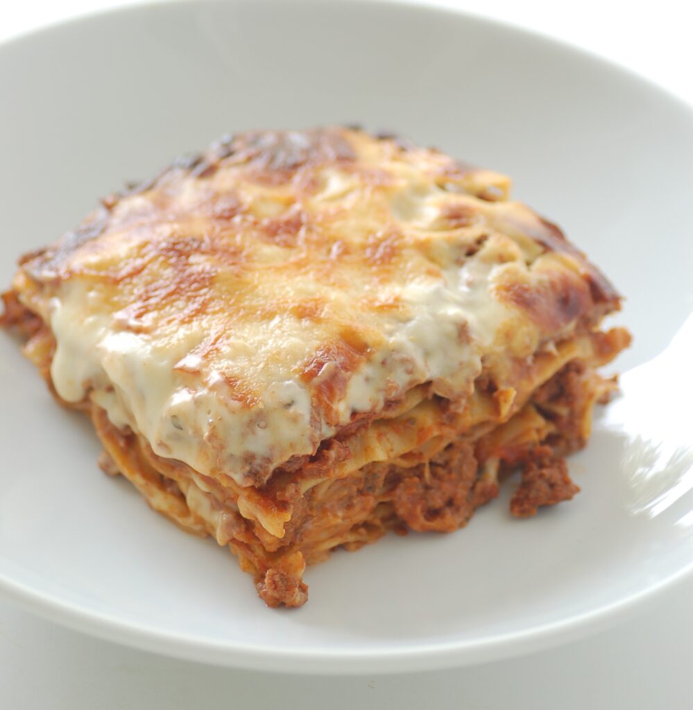 Freshly baked slice of classic beef lasagna with melted cheese on a plate