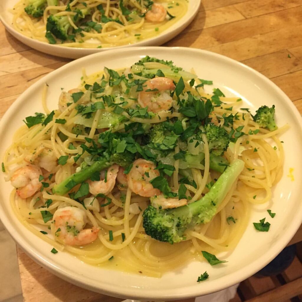 A bowl of Lemon Garlic Shrimp & Spinach Pasta garnished with fresh parsley, juicy cooked shrimp, and grated Parmesan cheese.